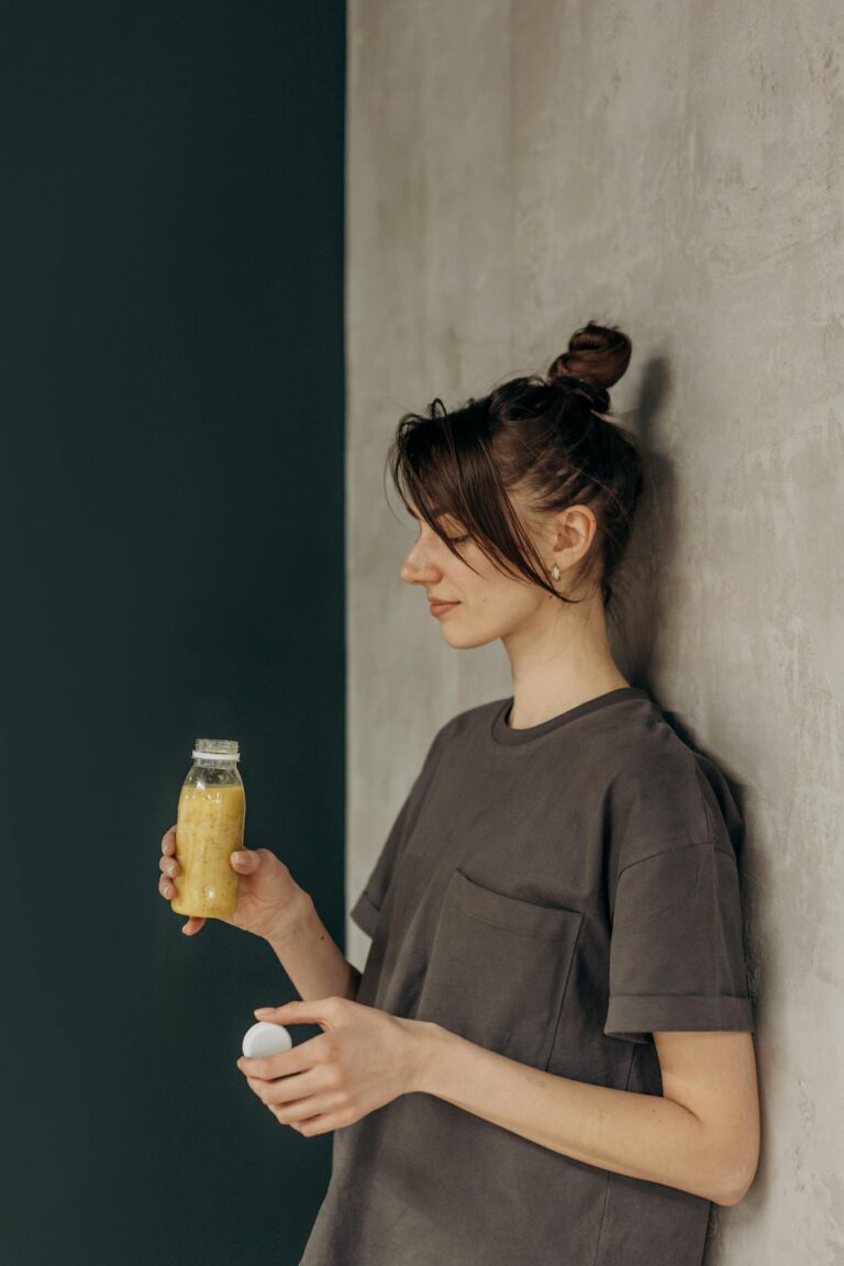 A young woman enjoys a fresh juice drink indoors, promoting a healthy lifestyle.