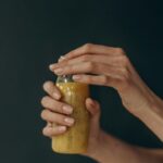Close-up of a woman's hands holding a refreshing smoothie bottle against a dark background.